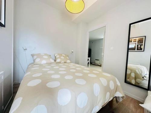 a white bedroom with a large bed and a mirror at La Laonnoise in Laon