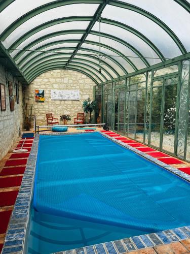 une piscine intérieure avec un bâtiment en verre dans l'établissement Château de la Thibaudière - Chambre des oiseaux, à Allonnes