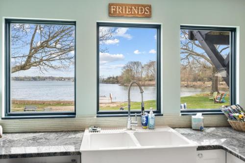 a kitchen with three windows and a white sink at 37 Wamphassuc Rd Chteau Stonington in Stonington