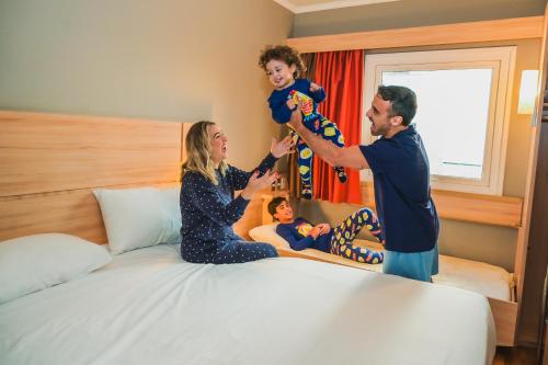a man and woman holding a child on a bed at ibis Santiago Las Condes in Santiago