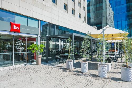 a store front with tables and chairs and potted trees at ibis Santiago Las Condes in Santiago