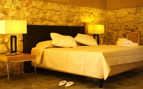 a bedroom with a bed with two lamps and slippers at Il Carosello dei Baroni in Noto