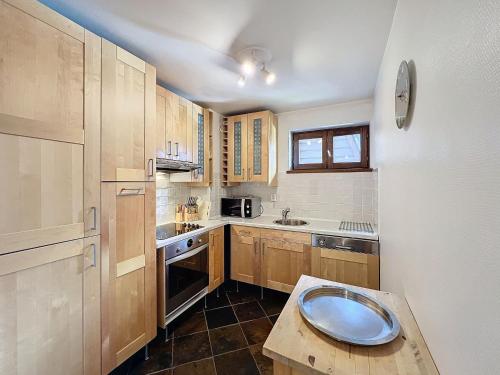 une cuisine avec des armoires en bois et une table à l'intérieur dans l'établissement Appartement Chamonix Centre, 4 Pers, 2 Ch. avec Balcon, Parking, Proche Téléphérique et Remontées - FR-1-507-24, à Chamonix-Mont-Blanc