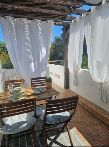 a table and chairs on a patio with white curtains at Casa Aventura in Boliqueime