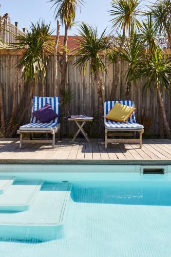 two chairs with pillows sitting next to a swimming pool at Beachfront House w Pool & Steam in West Wittering