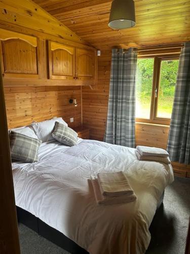 a bedroom with a bed in a wooden cabin at Lomond View Lodge in Glasgow