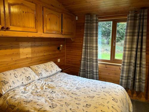 a bedroom with a bed and a window in a cabin at Lomond View Lodge in Glasgow