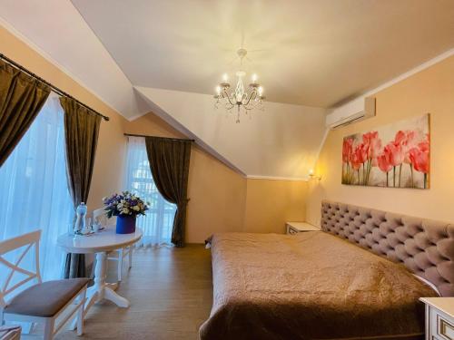 a bedroom with a bed and a table and a chandelier at Villa San Marino in Vorzelʼ