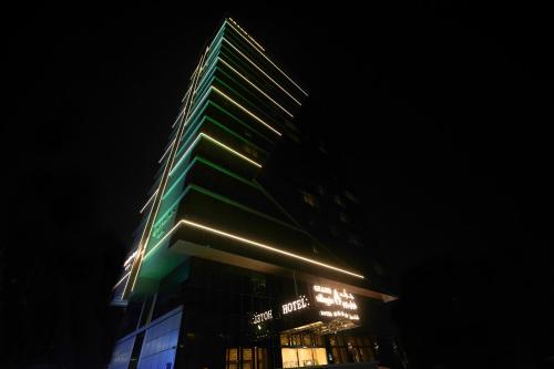 a tall green building with lights on it at night at Grand Villaggio Hotel Abu Dhabi in Abu Dhabi