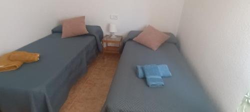 two beds in a room with blue sheets and pillows at adosado con piscina en Cabo de Gata 4p in El Cabo de Gata