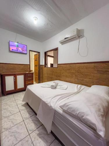 a bedroom with a bed and a tv on the wall at Pousada Territorial- Segunda praia MSP in Morro de São Paulo