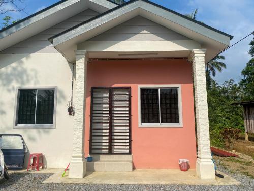 a small pink and white house with a door at Homestay Kak soh 2 at Kampung Kalai Jeli Kelantan in Jeli