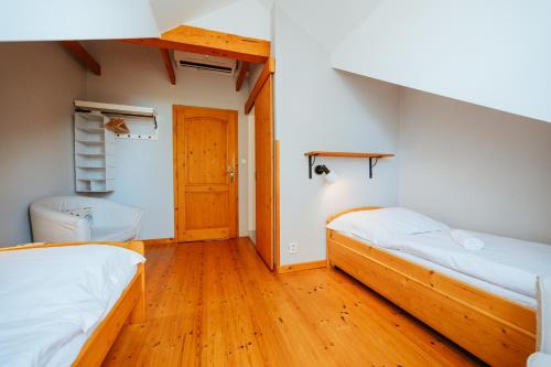 two beds in a room with wooden floors at Penzion U maléřa in Hroznová Lhota