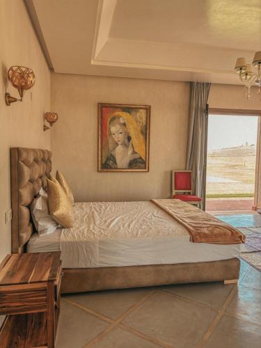 a bedroom with a large bed and a painting on the wall at Domaine Golfique Lamrah - 10 Suites in Marrakech