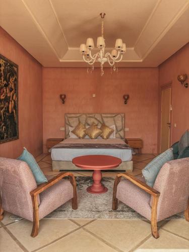 a bedroom with a bed and two chairs and a table at Domaine Golfique Lamrah - 10 Suites in Marrakech