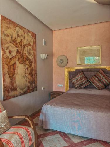 a bedroom with a bed and a painting on the wall at Domaine Golfique Lamrah - 10 Suites in Marrakech