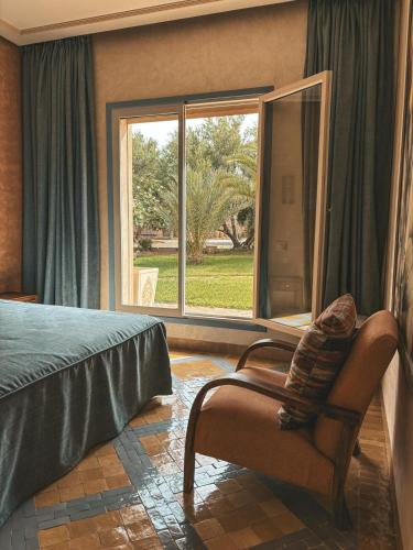 a bedroom with a bed and a chair and a window at Domaine Golfique Lamrah - 10 Suites in Marrakech