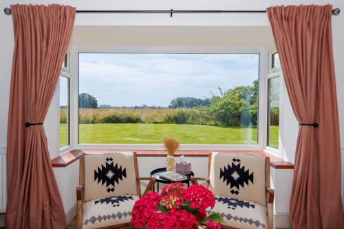 a dining room with a large window and a table and chairs at Idyllic 3 Bed Country Cottage in West Wittering