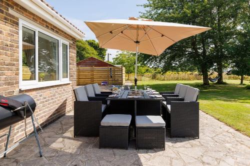 a patio with a table and an umbrella at Idyllic 3 Bed Country Cottage in West Wittering