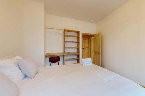 a bedroom with a white bed and a red chair at Hideaway House in Hope