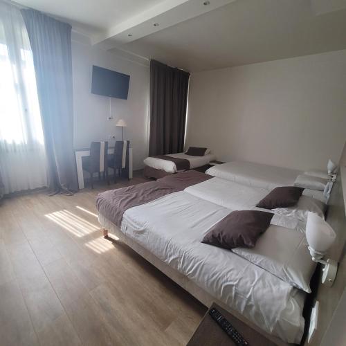 a hotel room with two beds and a table at KYRIAD ORANGE Centre Ville - HOTEL & RESTAURANT & BAR - La Galerie d'Art des Princes - Provence Alpes Côte d'Azur - France - Proche A7-A9 - exit21- Châteauneuf-du-Pape Avignon Bollene Nimes - 24h-24h in Orange