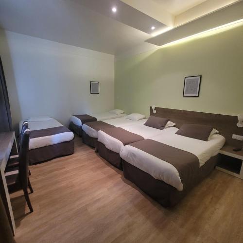 a room with three beds in it with a desk at KYRIAD ORANGE Centre Ville - HOTEL & RESTAURANT & BAR - La Galerie d'Art des Princes - Provence Alpes Côte d'Azur - France - Proche A7-A9 - exit21- Châteauneuf-du-Pape Avignon Bollene Nimes - 24h-24h in Orange