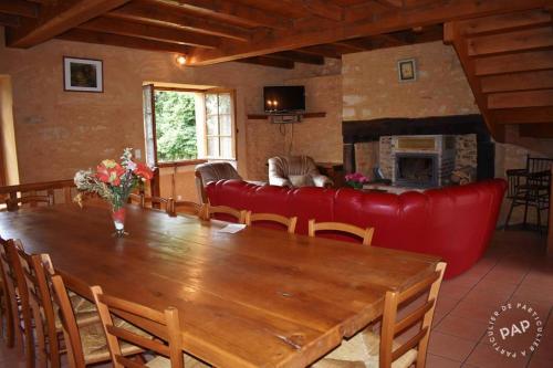 - un salon avec une table en bois et un canapé rouge dans l'établissement Gîte 14 personnes, à Villefranche-du-Périgord