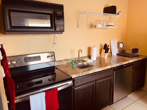 a kitchen with a stove and a microwave at REGENCY Inn & SUITES NEW LONDON MYSTIC in New London