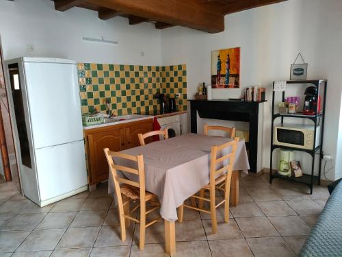 une cuisine avec une table avec des chaises et un réfrigérateur dans l'établissement OLMETA DI TUDA - T3, à Olmeta-di-Tuda