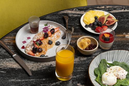 a table topped with plates of breakfast food and orange juice at Almanac Barcelona in Barcelona