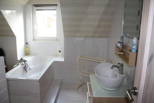 y baño blanco con lavabo, bañera y lavamanos. en Vakantiewoning Ijzerrust, en Roesbrugge-Haringe