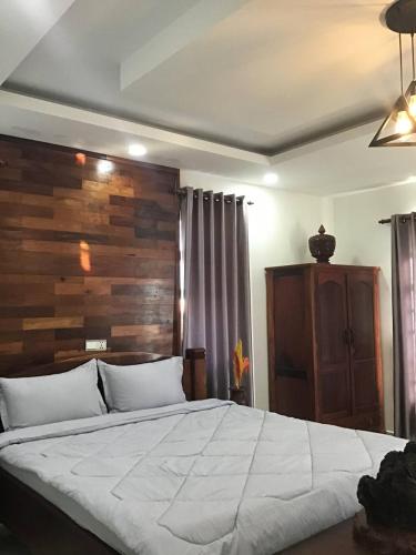 a bedroom with a large bed with a wooden headboard at Liza Boutique in Phumi Ta Phul