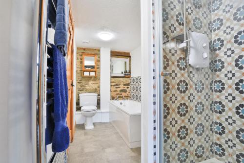 a bathroom with a toilet and a tub and a sink at Smiddy Cottage, Historic Village Hub with Spacious Lounge, High Ceilings, and Wood Stove in Dulverton