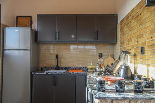 a kitchen with black cabinets and a white refrigerator at Smaylo Surf House in Sidi Kouaki
