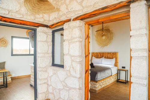 a bedroom with a bed and a stone wall at Smaylo Surf House in Sidi Kouaki