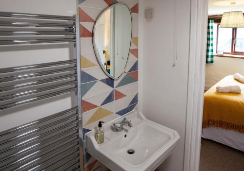 a bathroom with a sink and a mirror at Kiri - Charming Cottage Perfect for Large Groups & Family in Dulverton