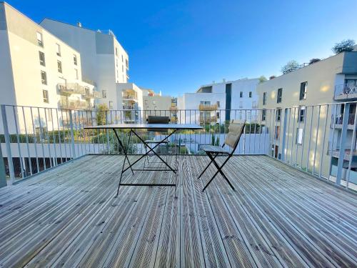 a table and a chair on a deck with buildings at Appartements avec Terrasse - Cite du Vin in Bordeaux