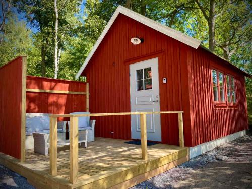 a red cabin with a deck in the woods at Bergs Gård & Hållsvikens Gård in Västerljung