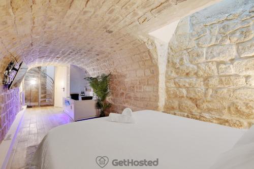 1 dormitorio con 1 cama blanca en una pared de piedra en Charming flat with Jacuzzi heart of Paris GetHosted, en París