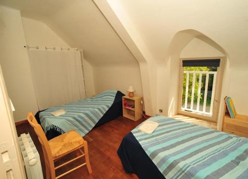 サン・クロンにあるGites Duguesclinのベッド2台と窓が備わる屋根裏部屋です。