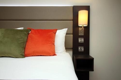 a bed with a red pillow and a lamp on it at Palette Modern Newport City Center in Newport