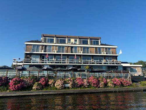 a large building with flowers in front of the water at Hotel aan de Linge in Kedichem