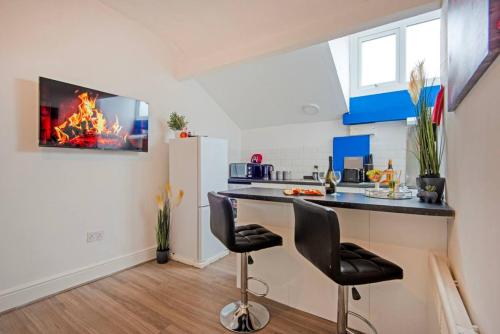 a kitchen with a counter with two chairs and a refrigerator at 5 minute walk from Bury city centre -1 bed flat in Bury