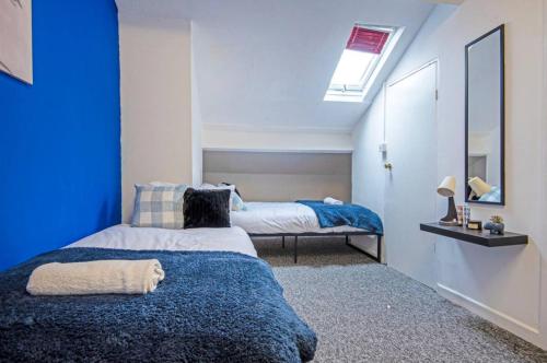 ベリーにある5 minute walk from Bury city centre -1 bed flatのベッドが2つあり、青い壁の寝室