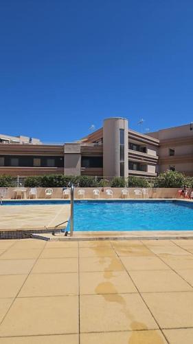 une grande piscine devant un immeuble dans l'établissement appartement terrasse vue mer, à Sète