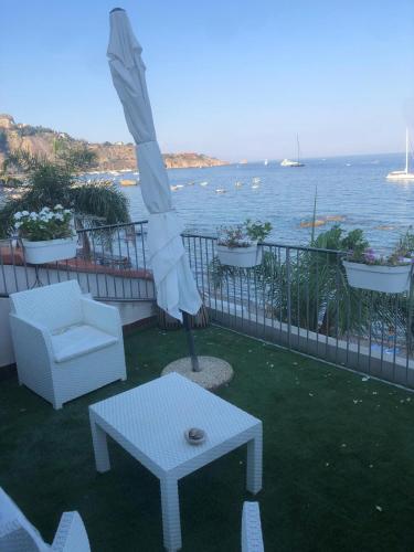 un patio con un tavolo, una sedia e un ombrellone di Home & Sea a Giardini Naxos