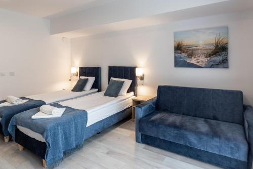a bedroom with two beds and a chair at Srebrna Wydma Resort in Dąbki