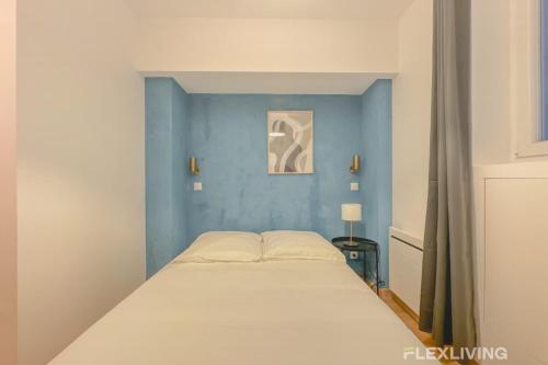 ein Schlafzimmer mit einem Bett mit einer blauen Wand in der Unterkunft Flexliving - room - Neuilly-sur-Seine in Neuilly-sur-Seine