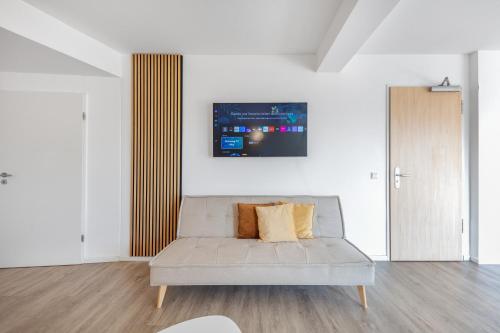 a living room with a couch and a tv on the wall at Mango Living I Apartment Hideaway I modern I 2 Schlafzimmer I 77qm in Mönchengladbach