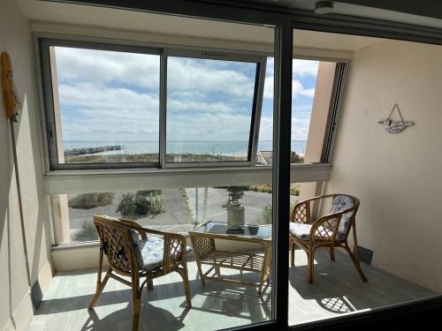 un balcon avec une table, des chaises et une fenêtre dans l'établissement L Arc en Ciel, à Saint-Jean-de-Monts